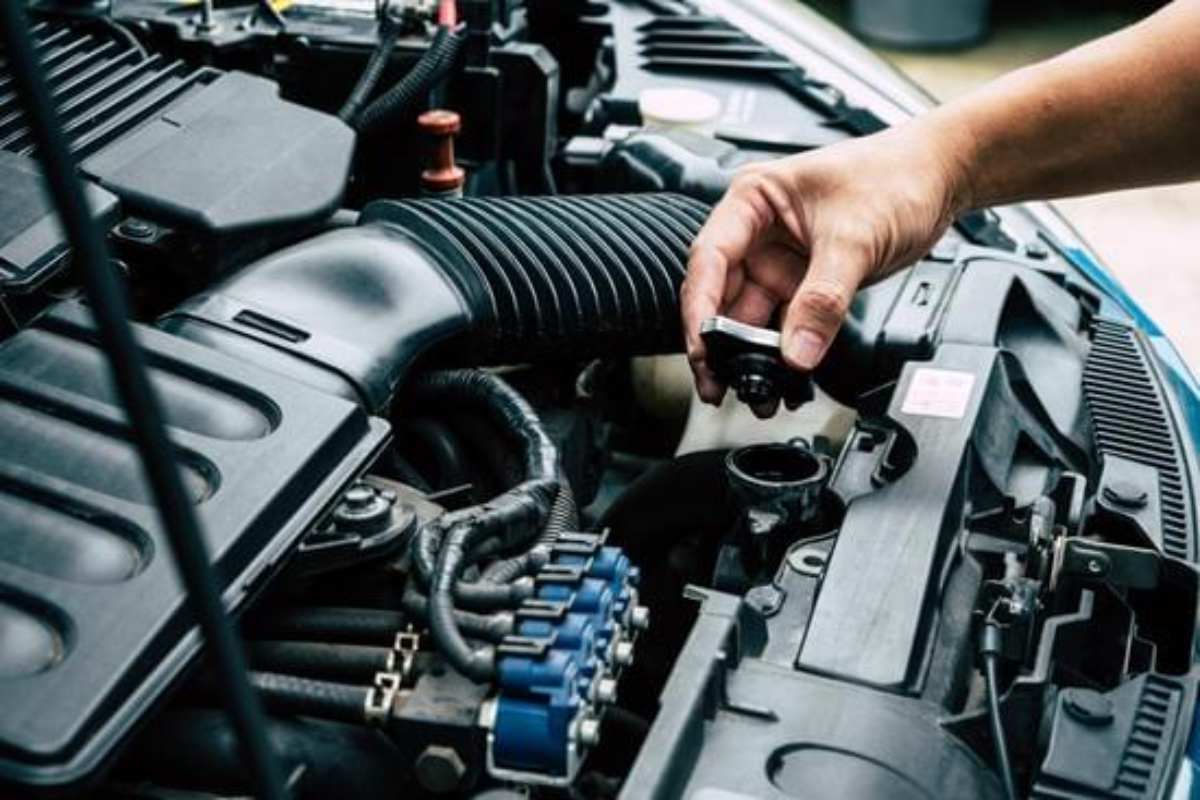Why Your Engine Overheats When the AC Is On Mechanic inspecting a car radiator, checking coolant levels to prevent engine overheating, with steam rising and warning sign 'Check the Radiator' visible.