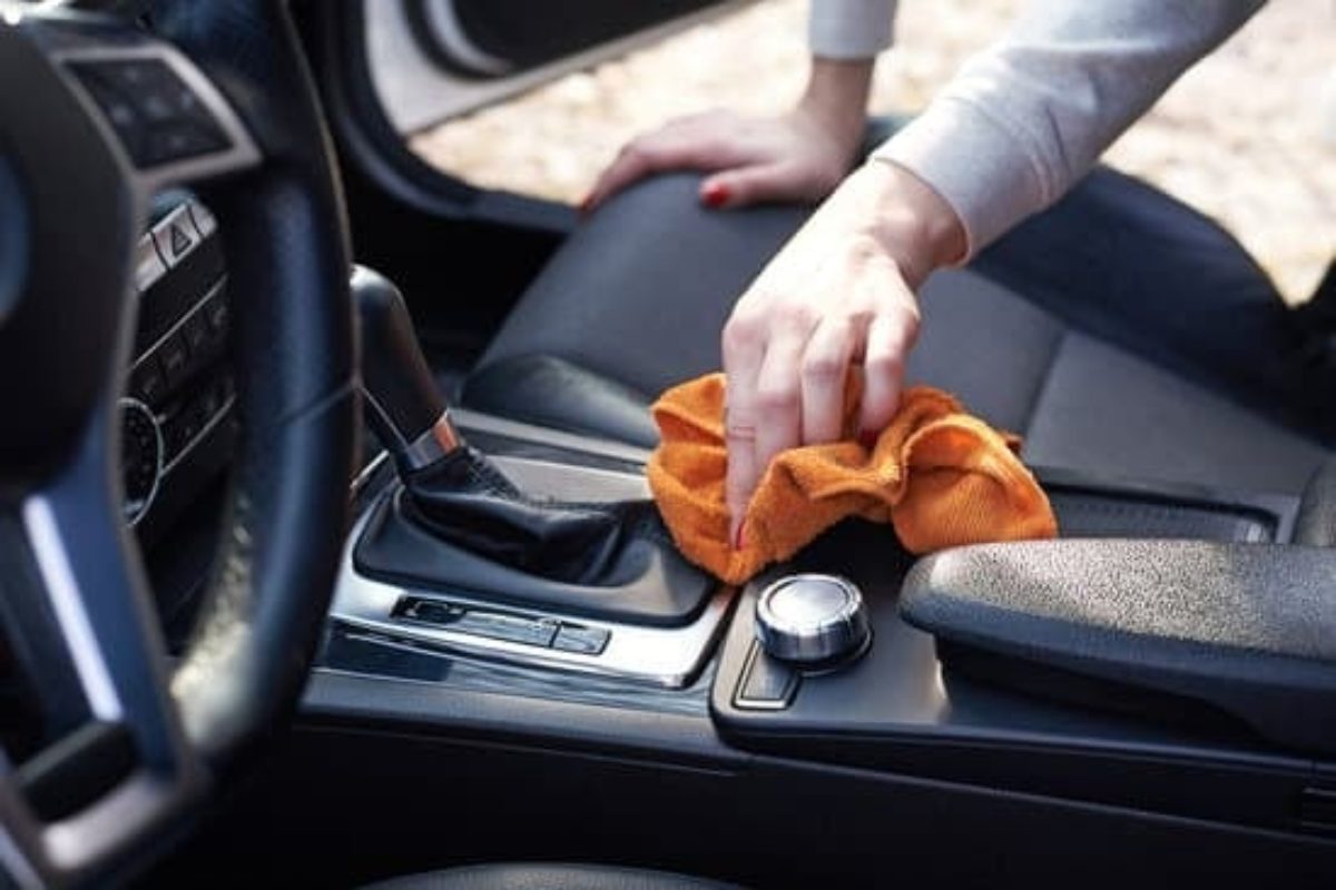 Mechanic drying a car engine bay with compressed air and microfiber cloths after cleaning