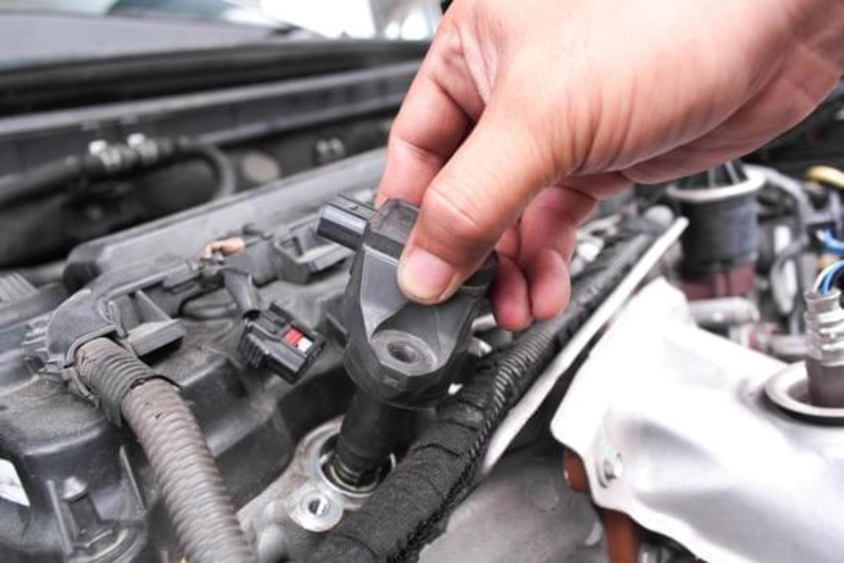 Person removing a faulty engine temperature sensor from a car engine.