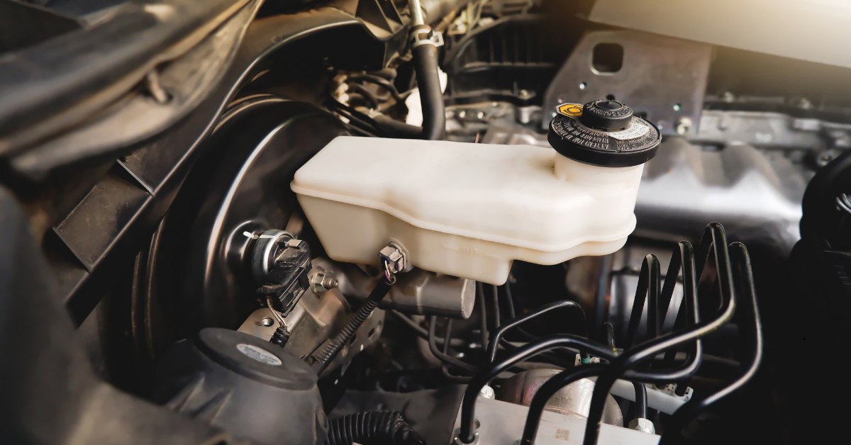 Car engine with white container showing hydraulic leak